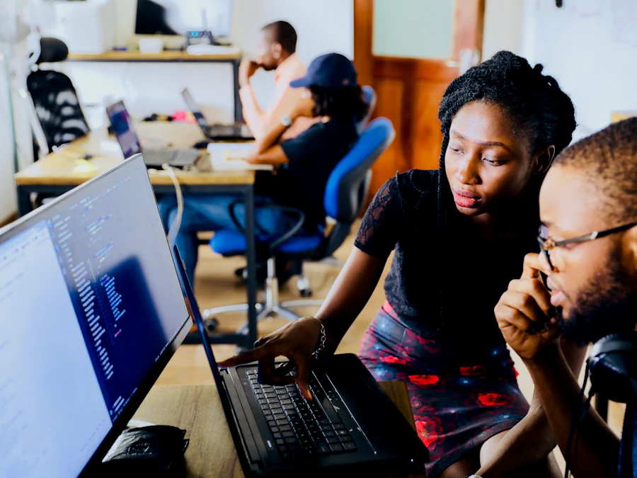 Two colleagues reviewing a data dashboard together on a desktop monitor