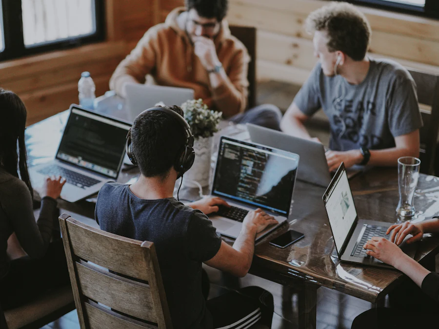 A project team working together on laptops around a shared wooden table